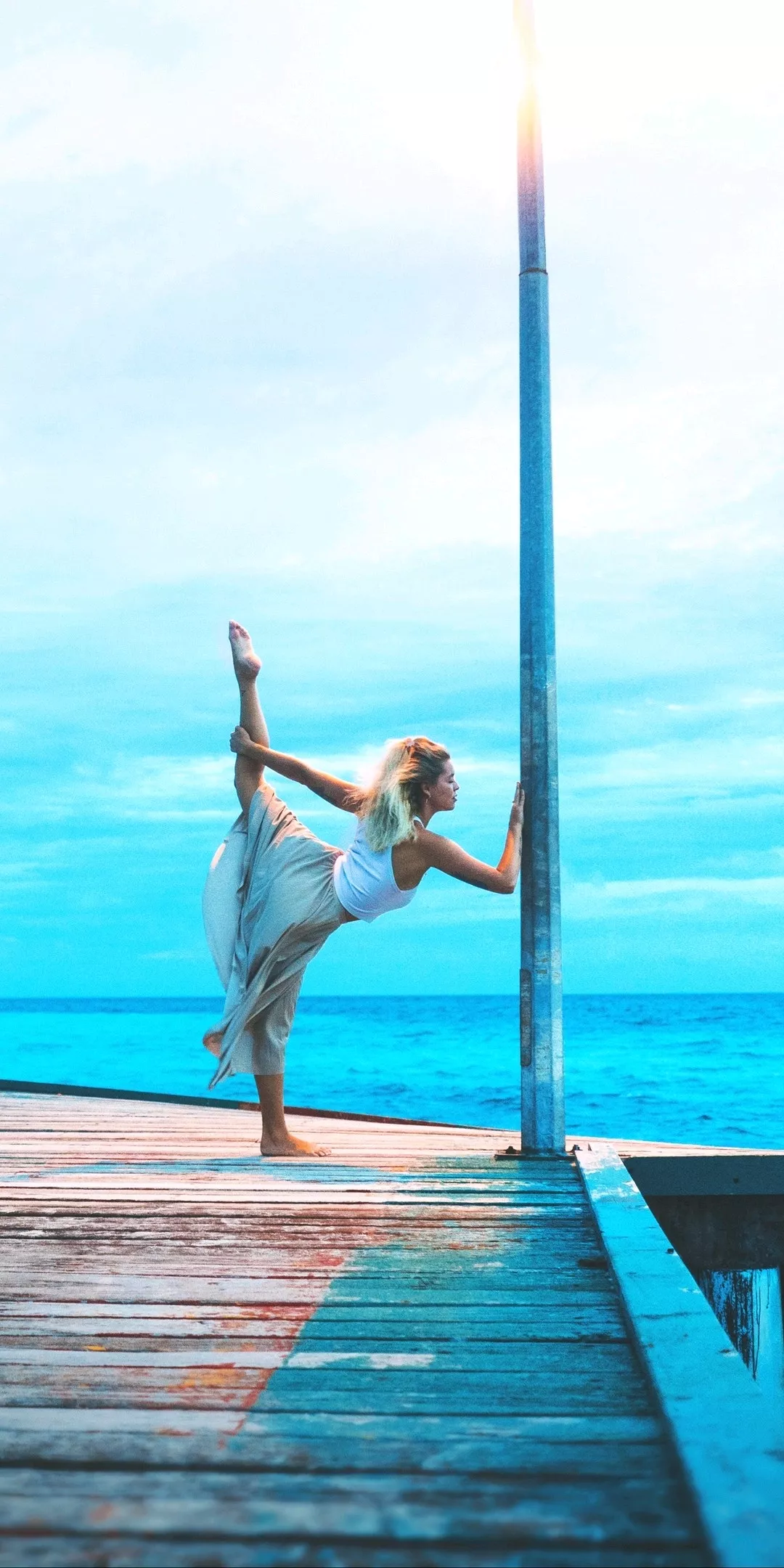 woman stretching on wooden dock while holding wallpaper